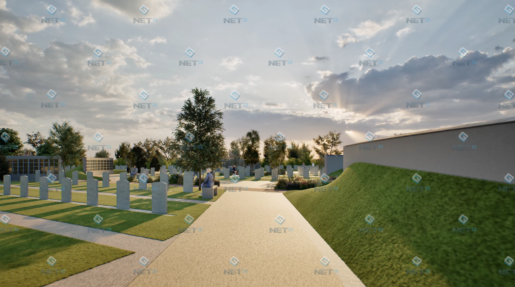 A mown path curving between earth berms and headstones at golden hour